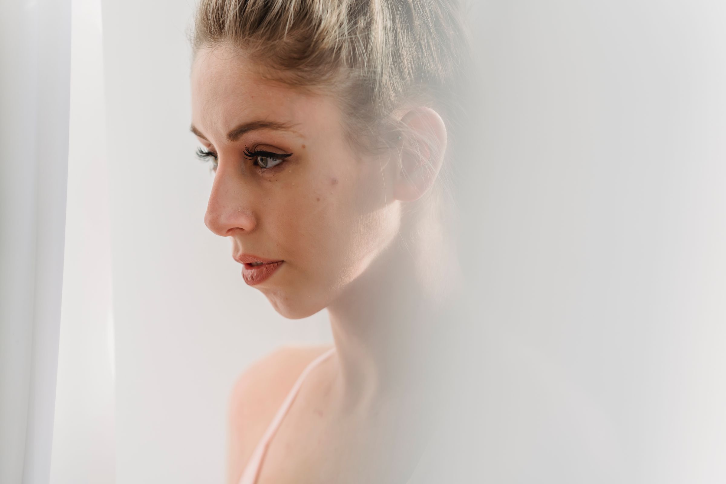 Side-profile portrait in soft window light.