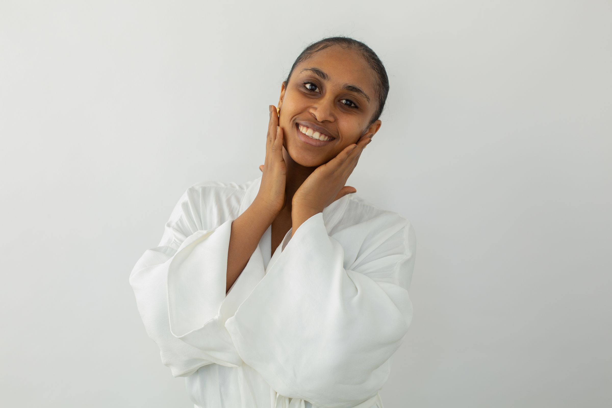 Smiling woman gently resting her hands against her cheeks.